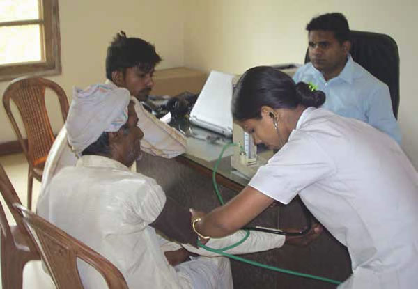 Alcuni membri del personale dell’ospizio esaminano un potenziale paziente [Foto di Ananta Simha Dasa].