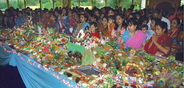 I devoti e gli ospiti ammirano un meraviglioso tavolo decorato con una moltitudine di varietà di maha-prasada.